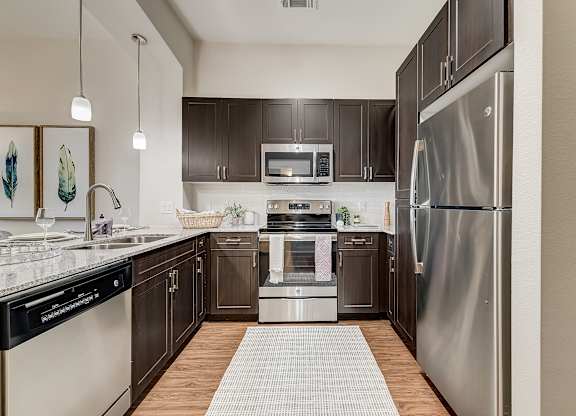 A modern kitchen with dark wood cabinets and stainless steel appliances.