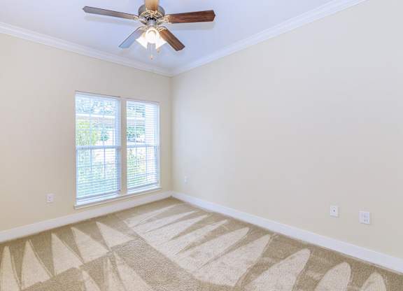 A room with a ceiling fan and a carpet on the floor.