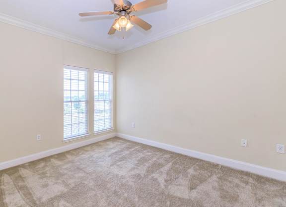 A room with a ceiling fan and carpeted floor.