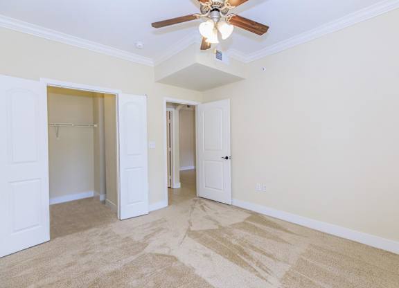 A room with a ceiling fan and carpeted floor.