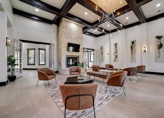 La Mirage clubhouse lounge with coffered ceiling, stone fireplace, and leather chairs.