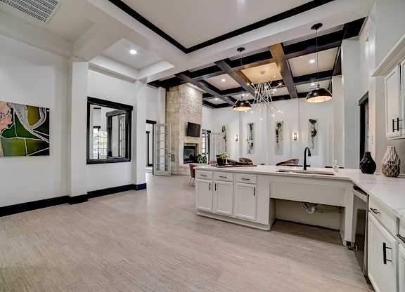 Community clubhouse kitchen island opening to spacious lounge with coffered ceiling.