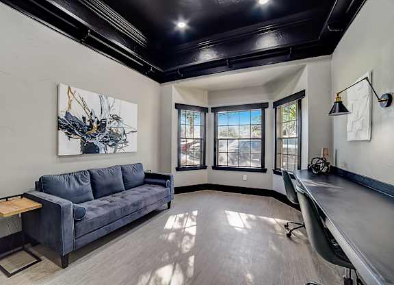 Coworking lounge with long work counter, rolling chairs, and natural light.
