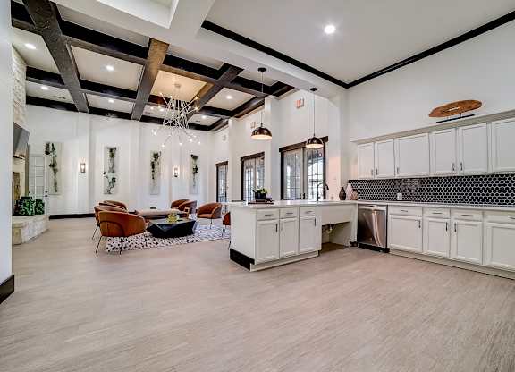 Wide view of clubhouse kitchen and lounge with island sink and coffered beams.
