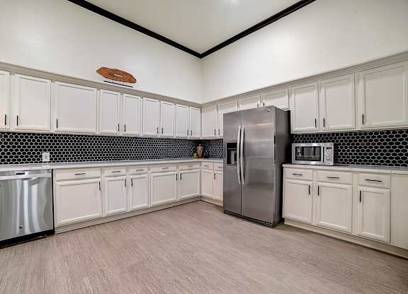 Clubhouse kitchen wall with extensive cabinetry, stainless appliances, and open floor space.