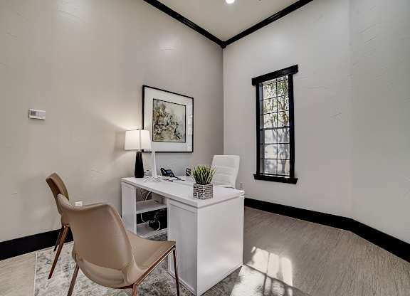 Leasing office workspace with desk, guest chair, and tall window with natural light.