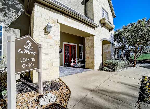 Leasing office exterior with stone façade, arched entry, and red double doors.