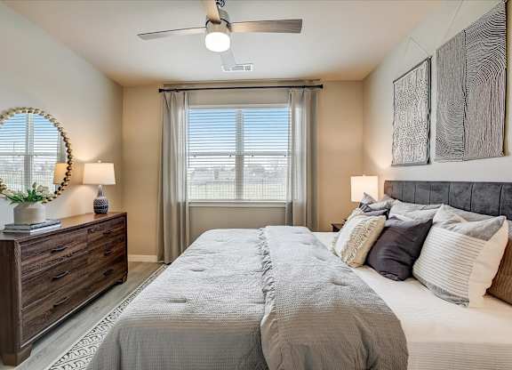 Secondary bedroom with gray upholstered headboard, dresser and mirror, and soft neutral bedding.