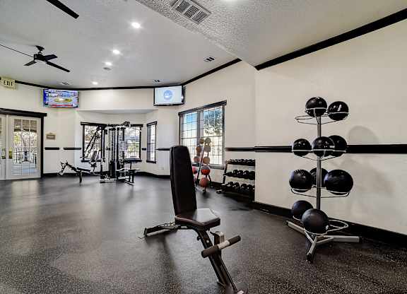Fitness center with weight bench, cable equipment, dumbbell rack, and medicine balls.