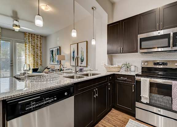 A modern kitchen with dark brown cabinets and stainless steel appliances.