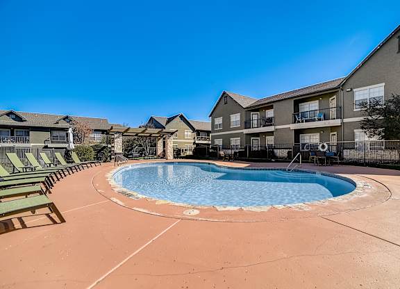 Community swimming pool with expansive deck, loungers, and shade pergola.