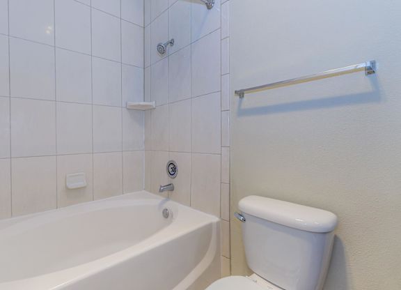 A white toilet sits next to a bathtub in a bathroom.