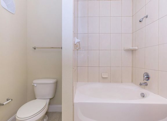 A white toilet and bathtub in a bathroom.