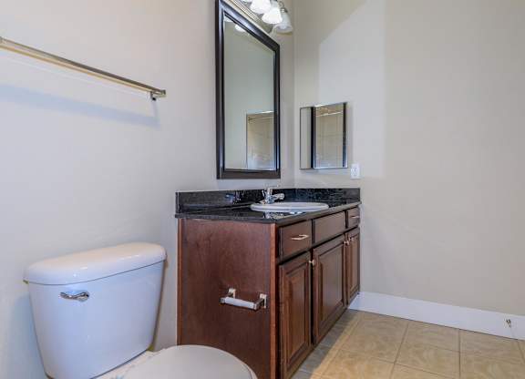 A bathroom with a toilet, sink, and mirror.