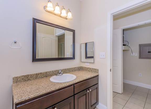 A bathroom with a sink, mirror, and light fixture.