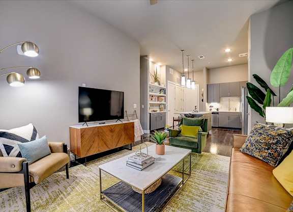 A modern living room with a flat screen TV, a coffee table, and a green chair.