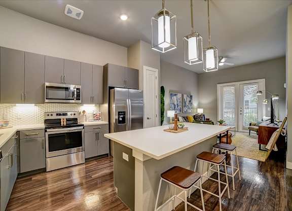 A modern kitchen with a large island and stainless steel appliances.