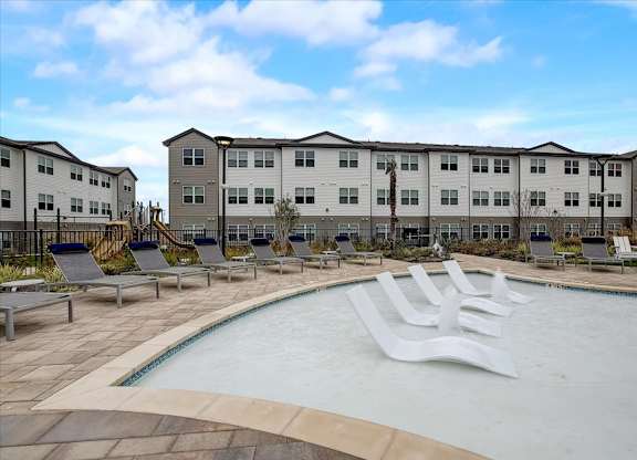 Shallow pool lounge section with in-water chaise seats, perimeter loungers, and open sky views.