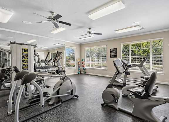 A spacious gym with a variety of exercise equipment and a fan.