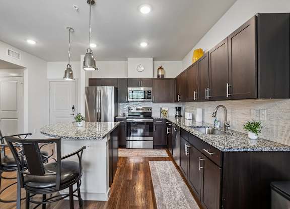 A kitchen with dark brown cabinets and a granite countertop.
