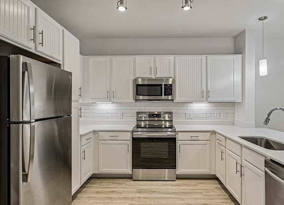 A modern kitchen with white cabinets and stainless steel appliances.