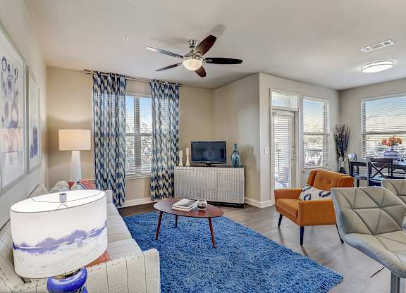 a living room with a blue rug and a ceiling fan