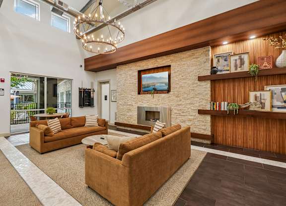 A living room with a stone fireplace and a chandelier.