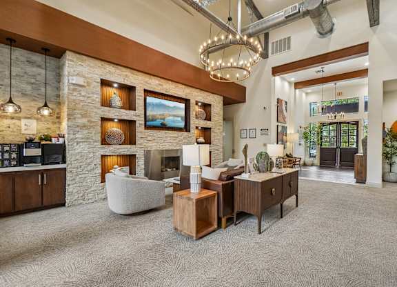 A modern living room with a stone fireplace and a large chandelier.