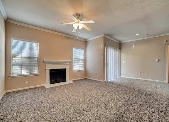 Spacious living room with fireplace, ceiling fan, and sliding glass doors.
