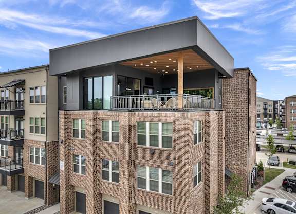 a brick apartment building with a balcony and a roof top terrace