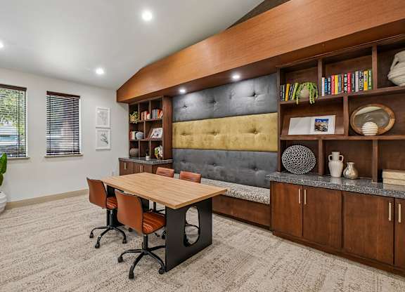 A room with a wooden table and chairs, a grey sofa, and a bookshelf with various items.