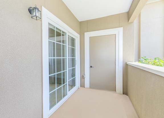 A hallway with a glass door and a white door.