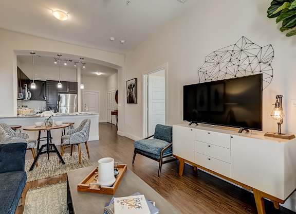A living room with a blue couch and a white cabinet with a television on top.