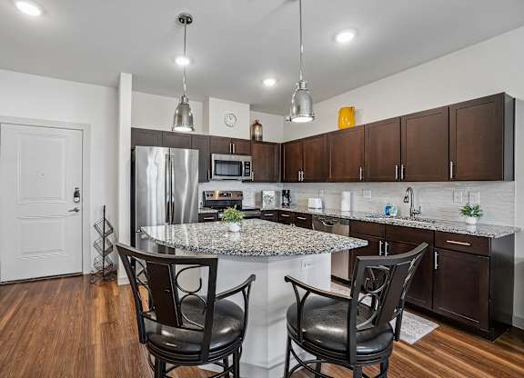 A kitchen with a granite countertop and a stainless steel refrigerator.