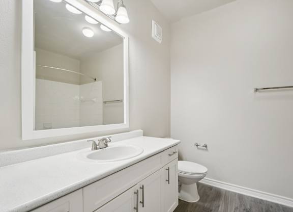A white bathroom with a sink, toilet, and mirror.