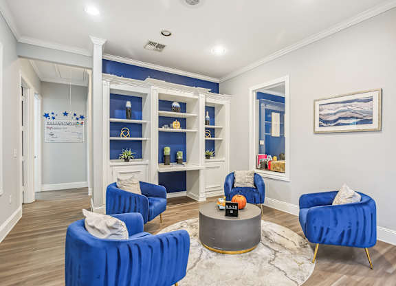 A living room with blue chairs and a grey coffee table.