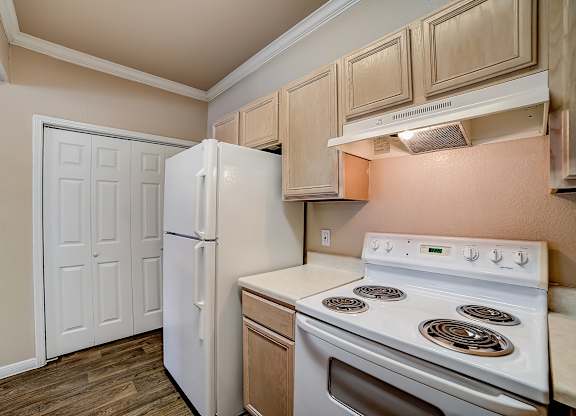 Kitchen corner with electric range, white refrigerator, and ample upper cabinets.