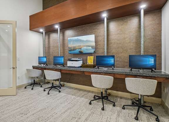 A room with a desk and chairs with a painting on the wall.