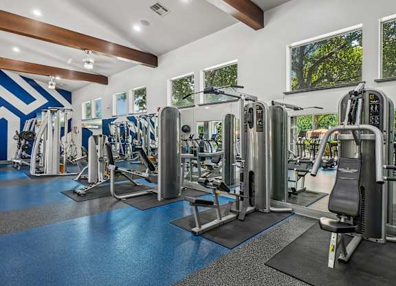 A gym with a variety of equipment including treadmills, weights, and exercise machines.