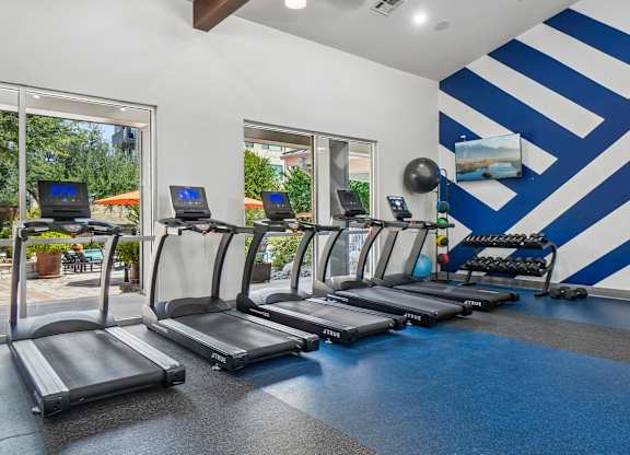 A gym with treadmills and a blue and white striped wall.