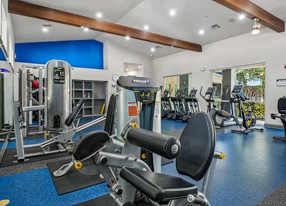A gym with a variety of equipment including a stationary bike and a leg press machine.