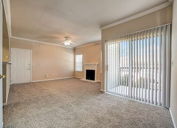 Living area with vertical blinds, patio access, and cozy corner fireplace.