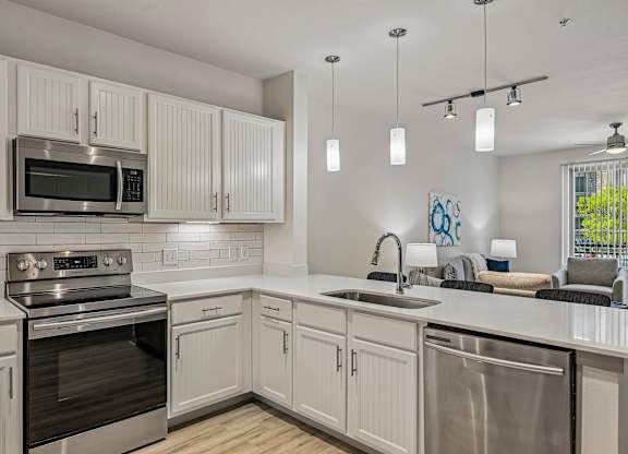 A modern kitchen with white cabinets and stainless steel appliances.