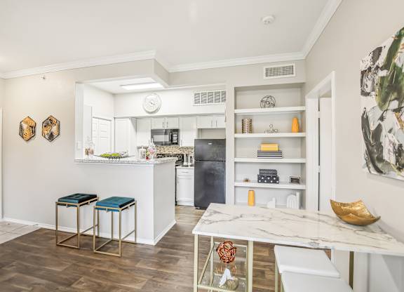 A kitchen with a white counter top and bar stools.