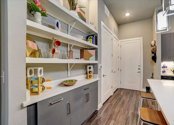 A kitchen with white countertops and grey cabinets.