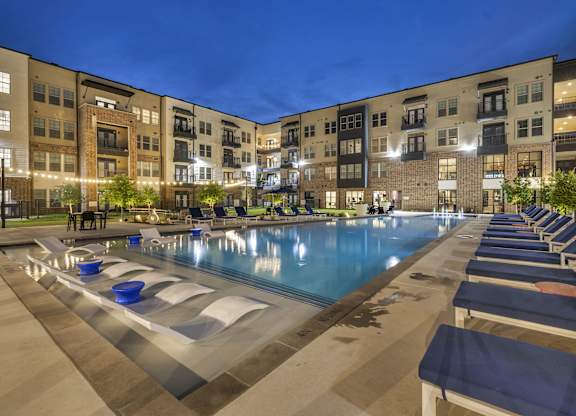 an outdoor pool with lounge chairs at night