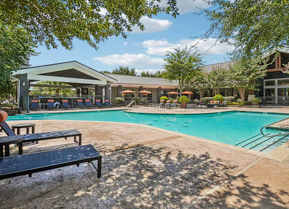 A pool area with a bench and a building in the background.