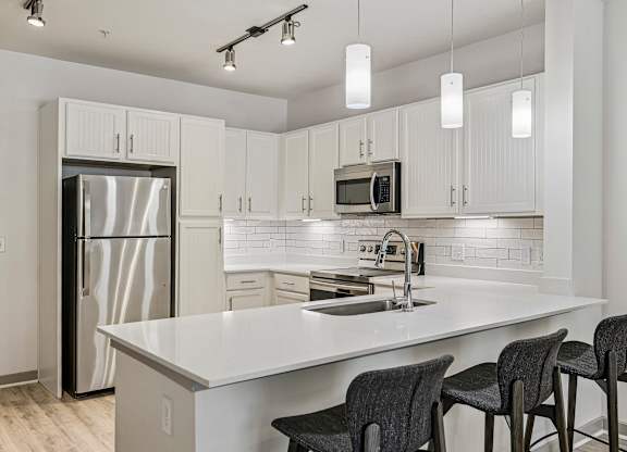 A kitchen with a white countertop and a stainless steel refrigerator.