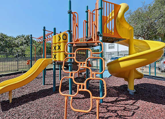 A playground with a yellow slide and orange climbing structure.