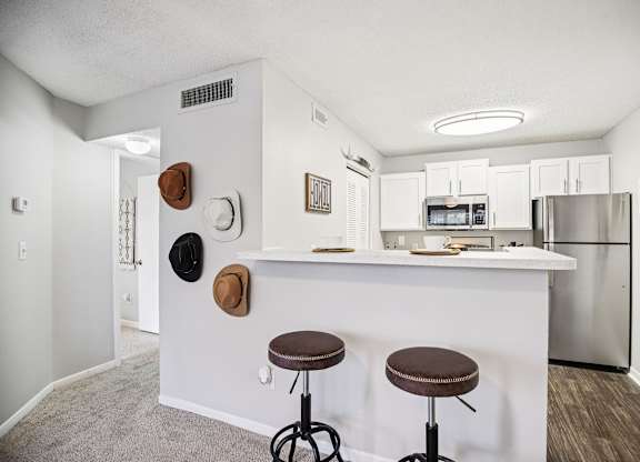 A kitchen with a white counter and two stools.